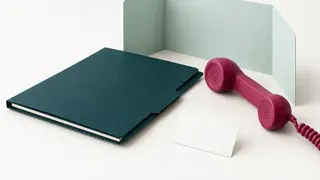 A closed folder, privacy screen, telephone handset and blank appointment card.